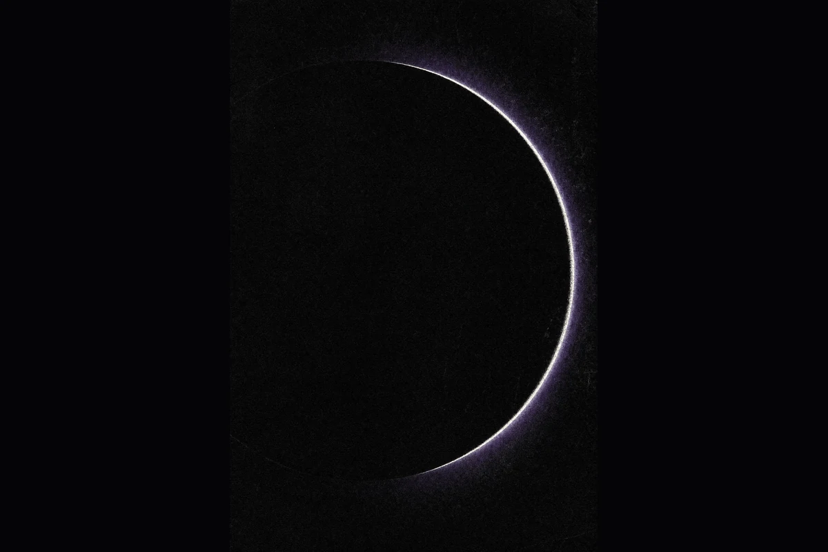 The unlit side of a moon as a black disc in a black frame, outlined by one thin bright arc of light with a faint violet glow.